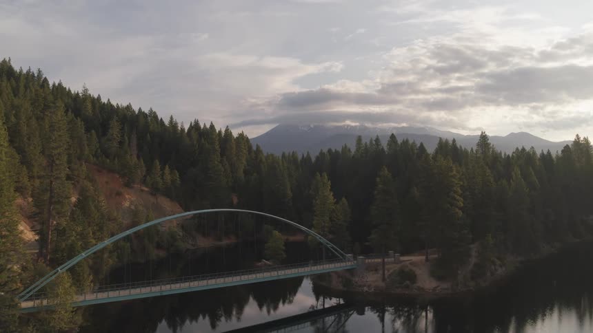 A lake surrounded by mountain and dense forest on a sunny day