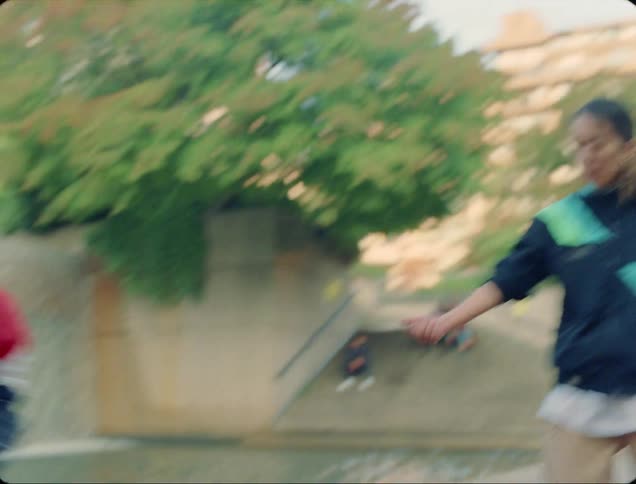 A man and woman take turns breakdancing on a dance mat in front of a fountain in a city park during the day
