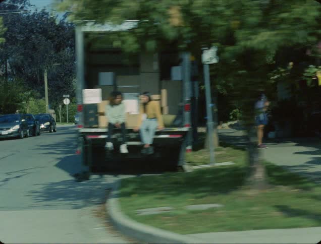 A view of shops and cars and people on a city street seen from inside a driving car