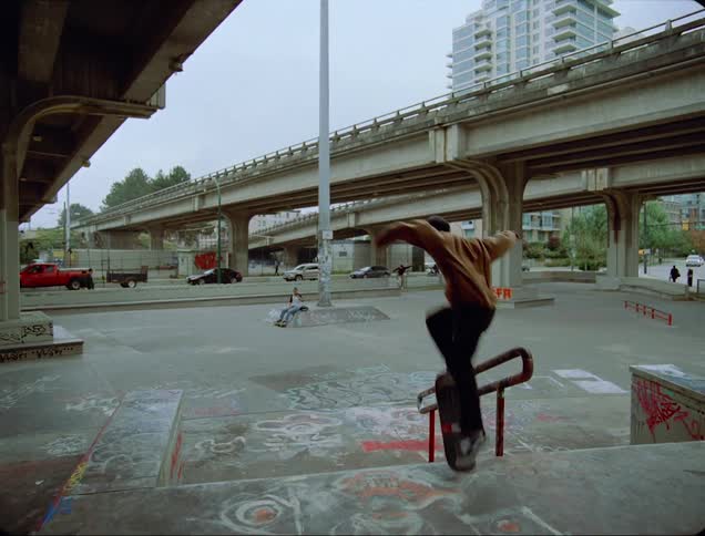 A group of males ride skateboards and jump over a small city staircase