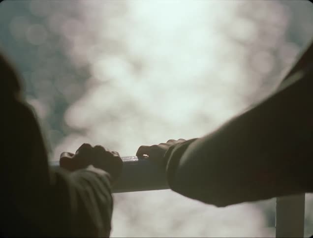 Two people stand on a balcony on a windy day overlooking the ocean