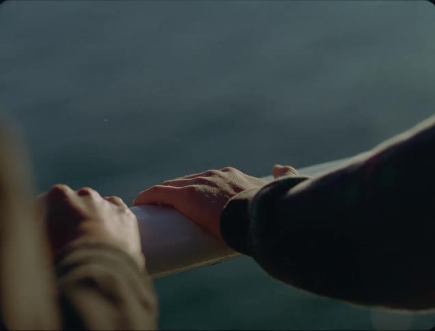 Two people holding on to hand railing with their hands with a river in the background