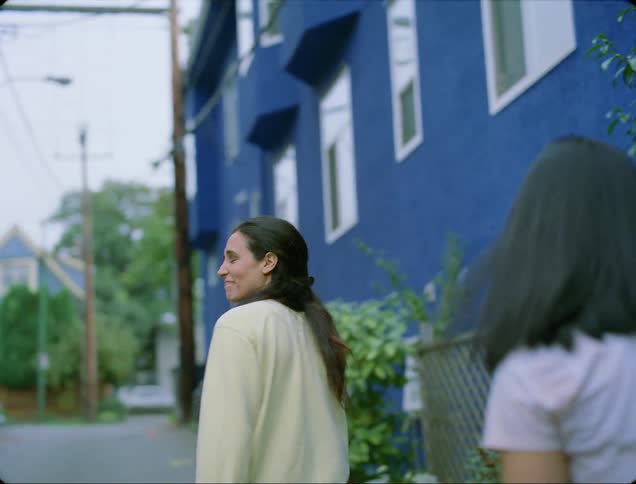 A woman waves goodbye to someone and her daughter walks a dog
