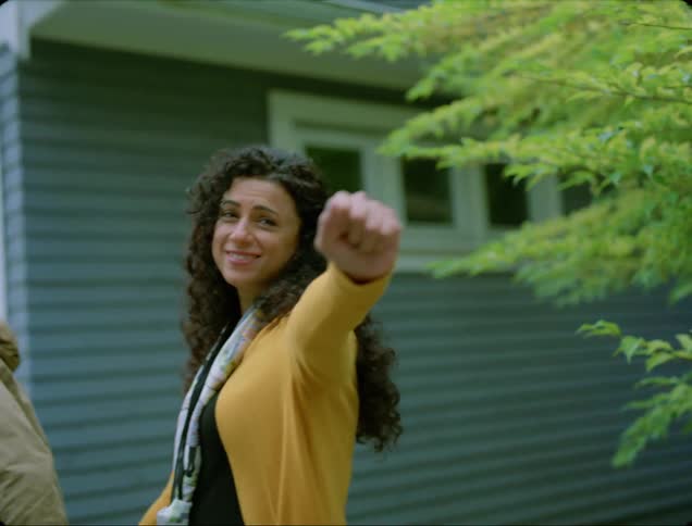 Couple leave hand in hand waving as they walk past garage doors