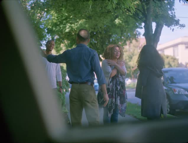 A couple runs out of their home to greet another couple on the sidewalk