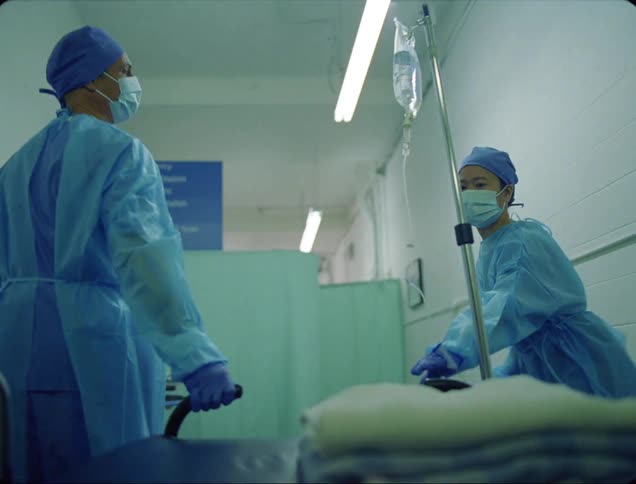 Healthcare employees moving gurney down hallway