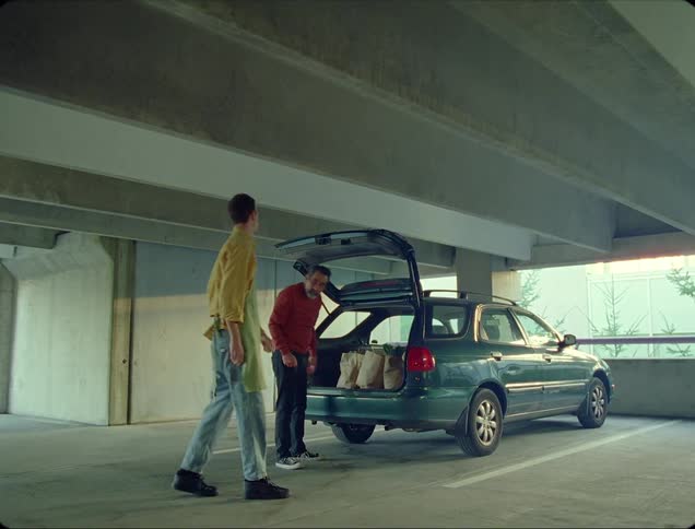 A store employee helps a man load shopping bags into his vehicle