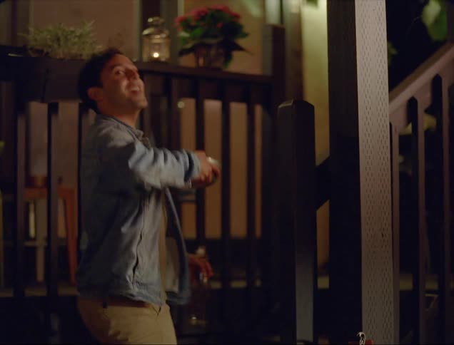 A man walks up the front porch steps of a home at night