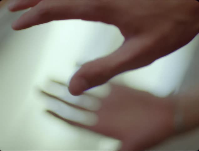 A white person with a bracelet on is lifting their hand on and off of a mirror
