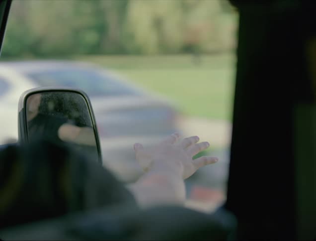 A person riding in a vehicle with their hand out the window