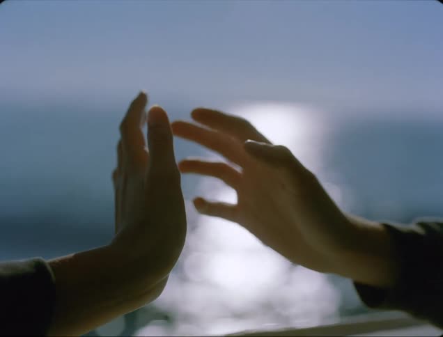 A person outside holds her hands up to one another and turns them both in the air