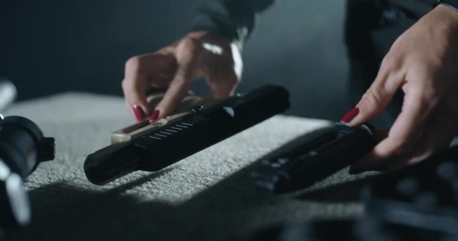 A woman unloads a pistol before sitting it on a table