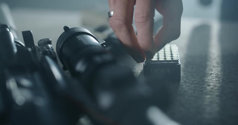 A woman removes a bullet from a pack to load her gun