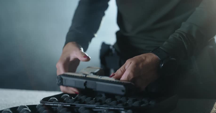 A woman removes a pistol from its case and pulls back its slide
