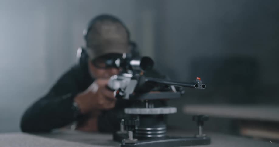 A man indoors shooting a gun