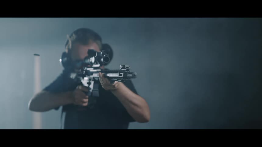 A man with earmuffs shooting a rifle with a scope