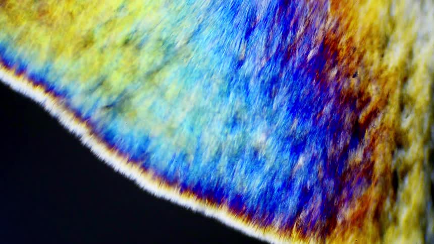 A chemical reaction where crystals form under a microscope