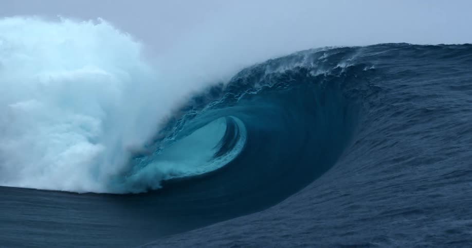 A large wave crashes into the ocean