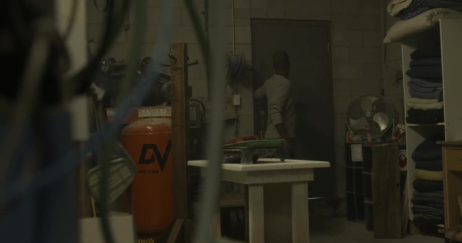 A man enters a workshop and turns on the light
