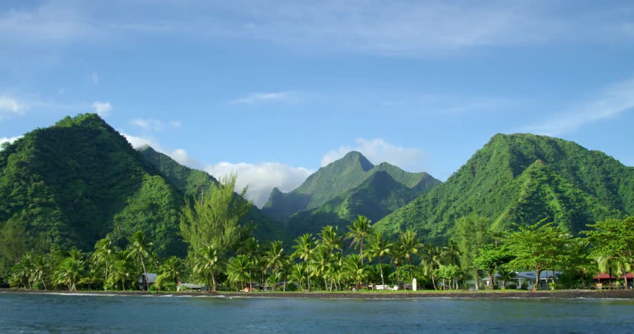 Small houses sit along the coast of a tropical island