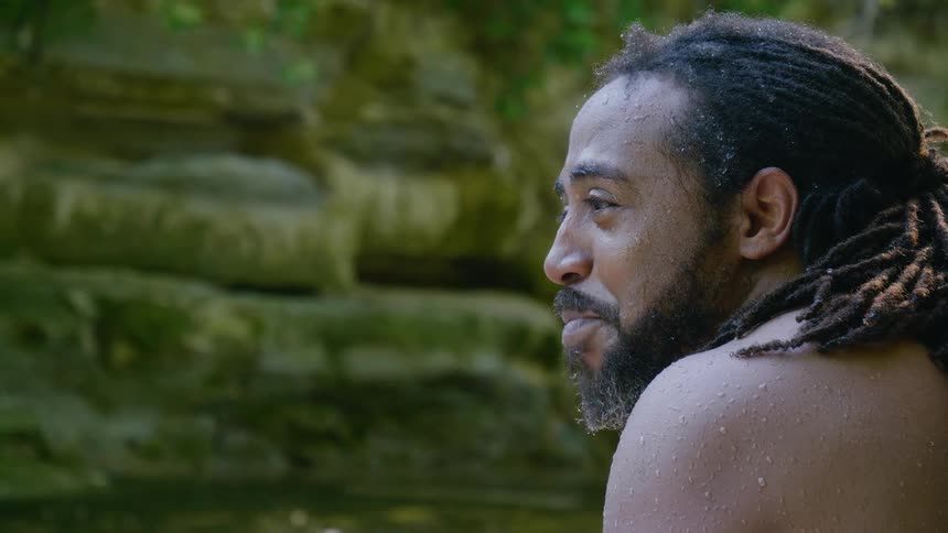 A wet man is talking by the water