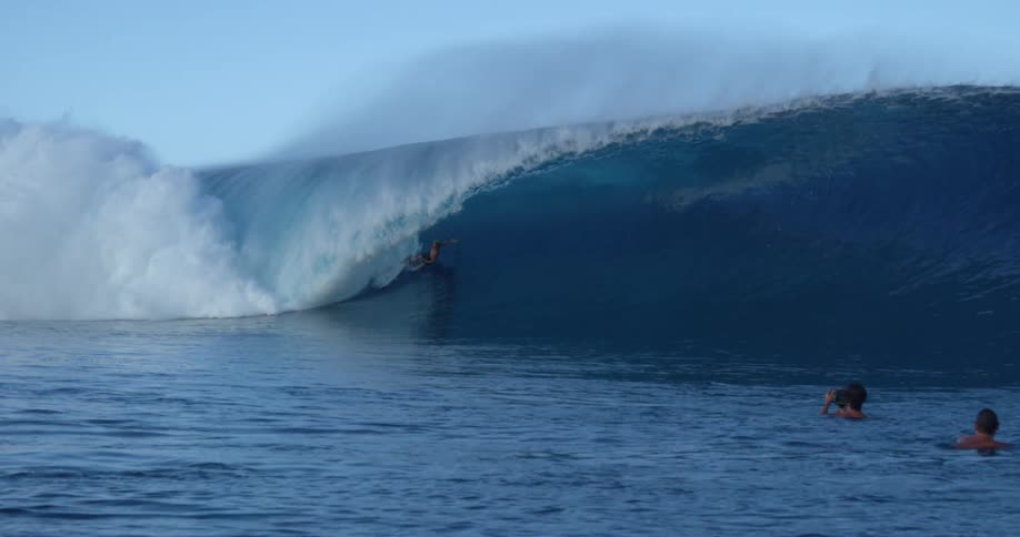 Group of surfboarders on large wave crashing in ocean