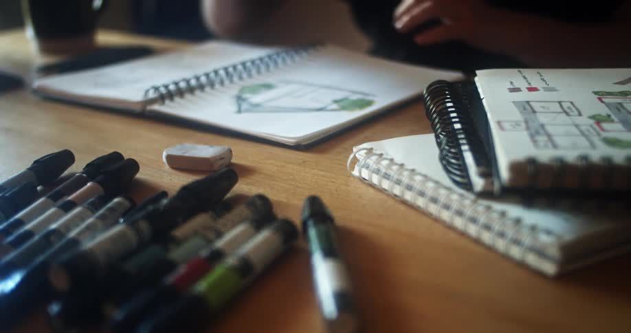 Person drawing with art markers in sketchbook on table