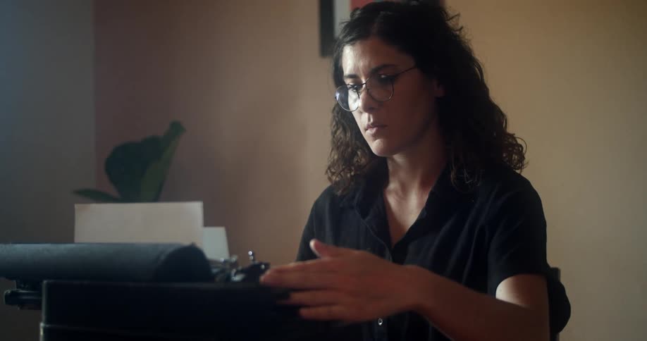 A woman is typing on a typewriter indoors