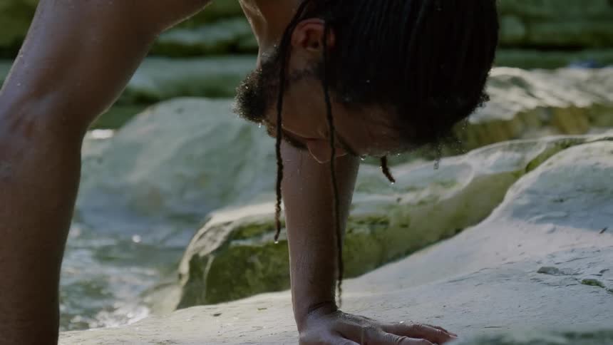 A man does a handstand by the stream