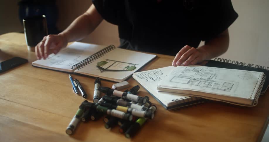 A woman in her office looks at floor plans and sketches on a picture of a home