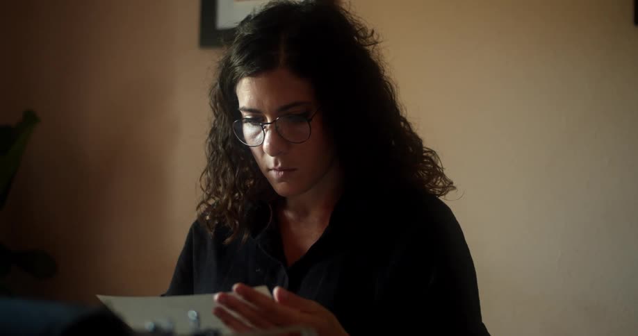 A woman removes a typed piece of paper from the typewriter