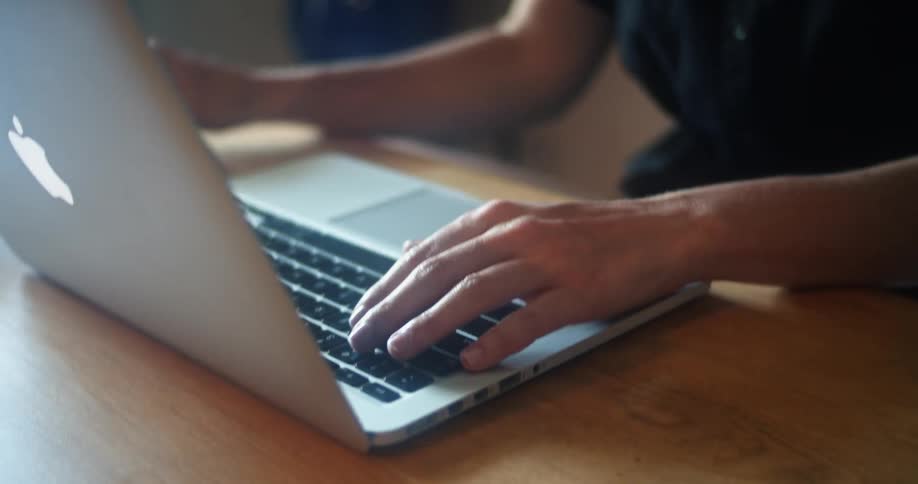 A woman puts down a phone and begins typing on a laptop