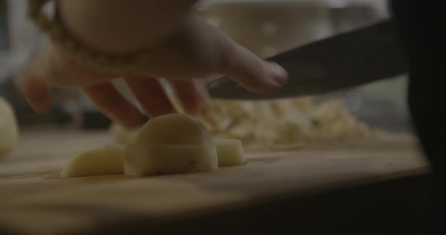 A person is cutting potatoes on a cutting board