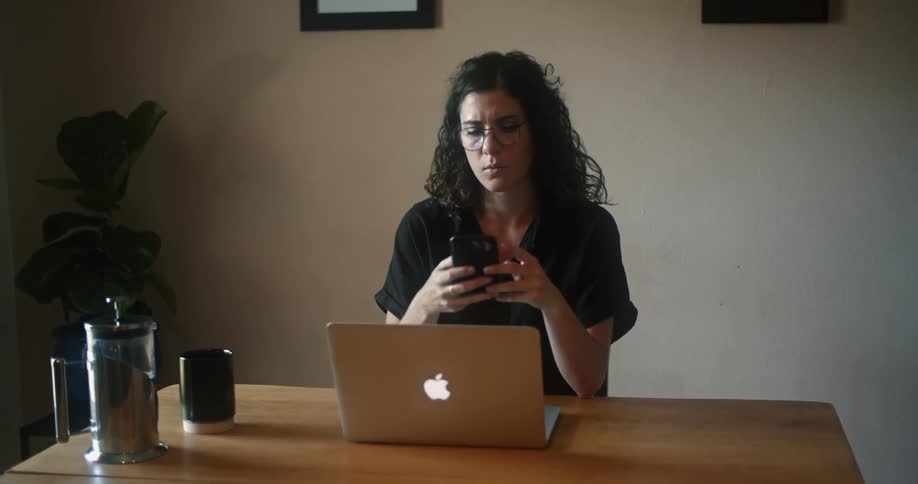 A woman is sitting indoors by a laptop