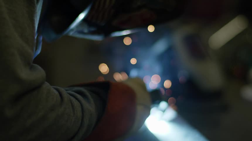 A man welding on a piece of metal in a shop