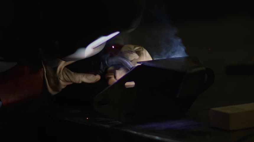 Sparks fly as a welder holds a torch to a piece of metal