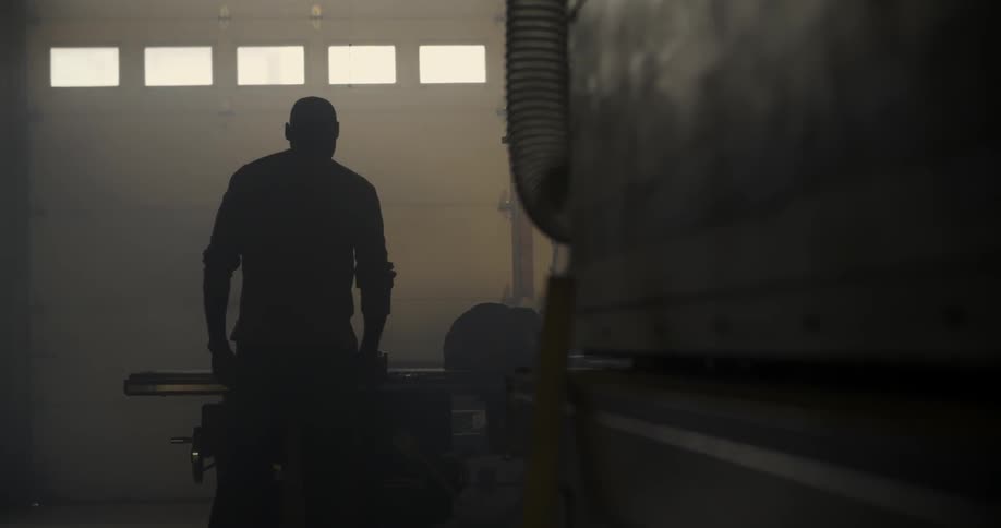 A man stands in the shadows of a workshop