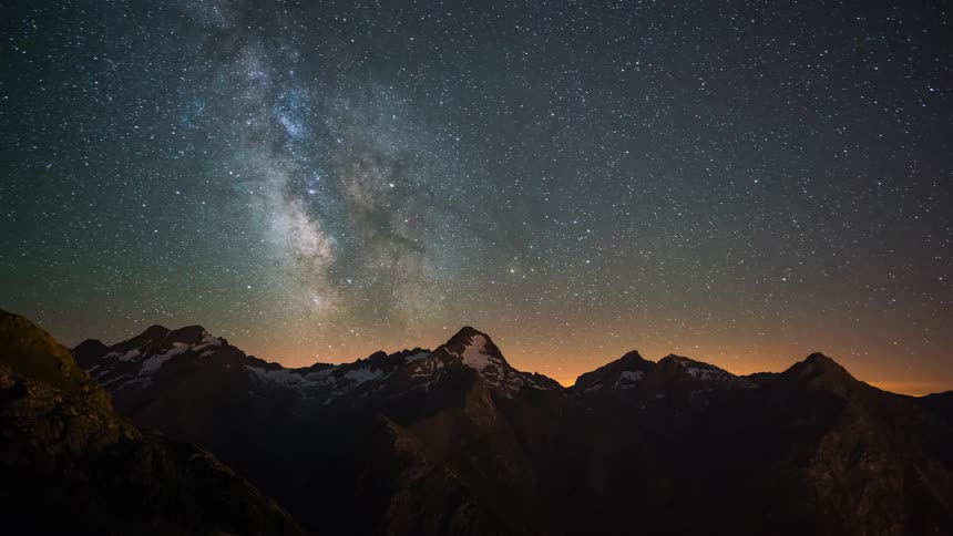 Stars and nebula flow across sky as sky brightens over mountains