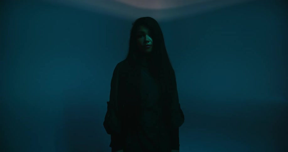 A teenage girl stands in a room with a bright red light flashing