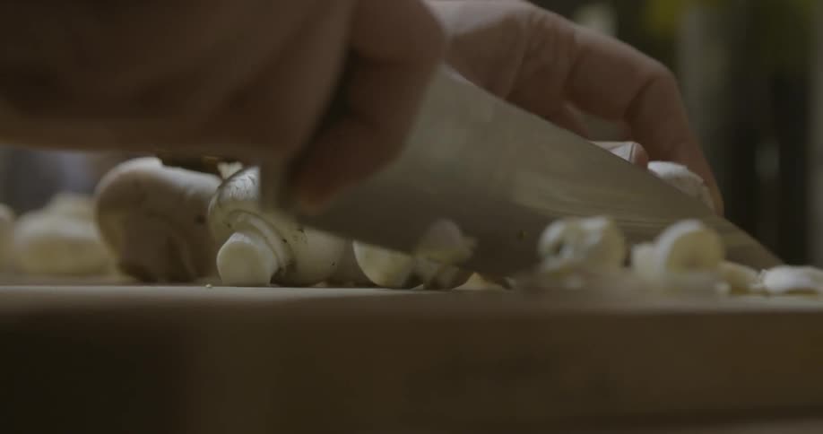 A person is cutting mushrooms on a board