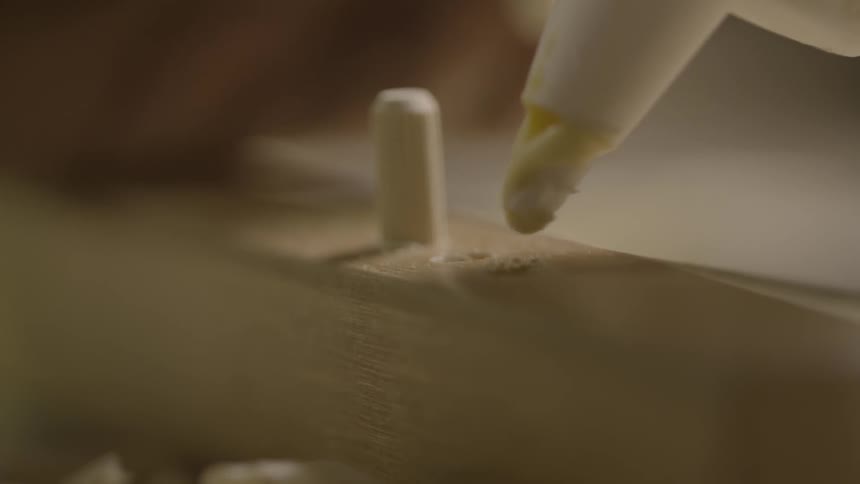 A person fills wood holes with glue and a small peg