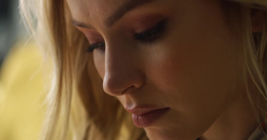 A woman with long blonde hair looks downward while concentrating