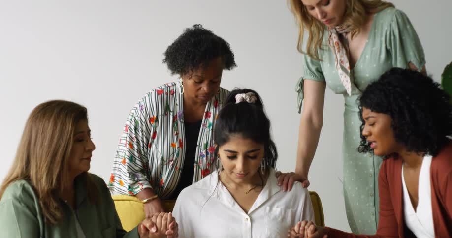 A group of women hold hands and pray