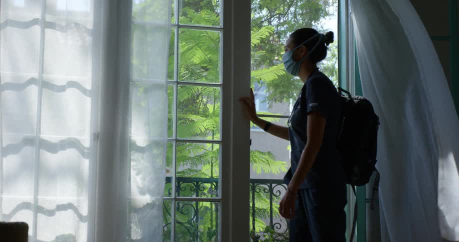 A nurse turns from her terrace and walks inside