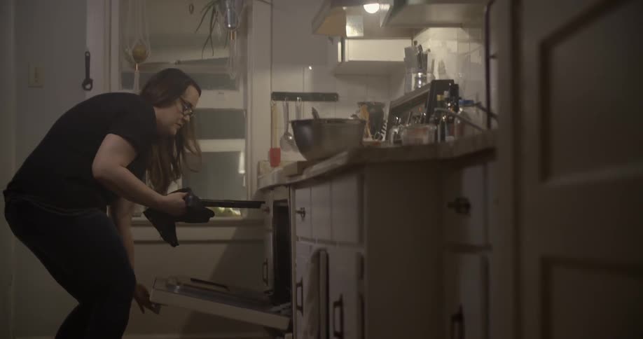 A woman removes a pan from an oven and places it down