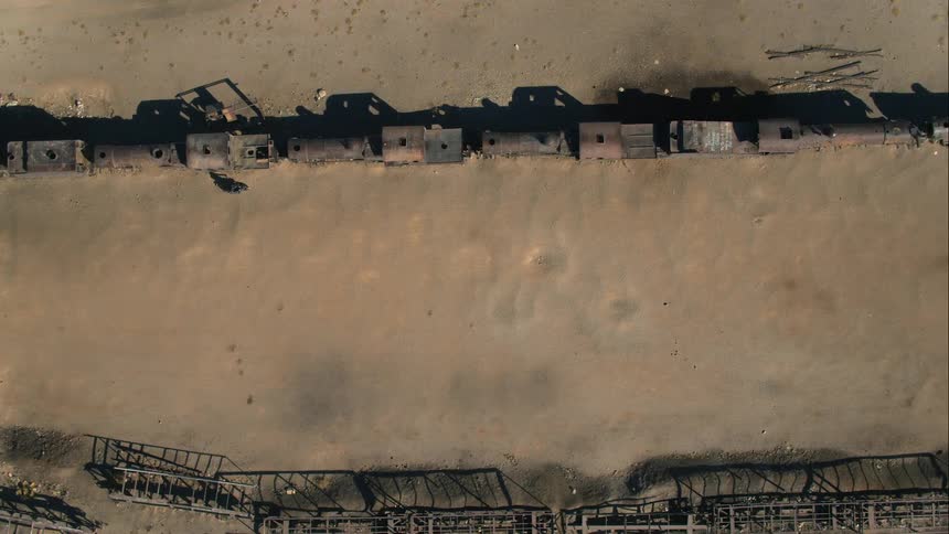 Aerial view of a man riding a motorcycle along the train wreck in the forest