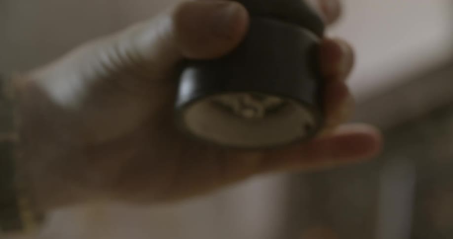 A hand holds and turns a pepper grinder