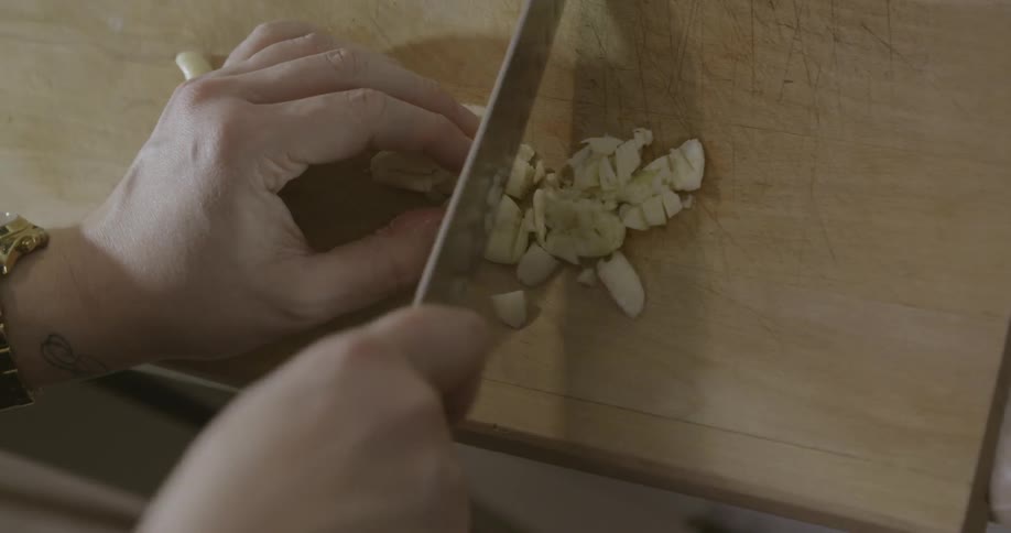 A person is cutting some garlic on a board