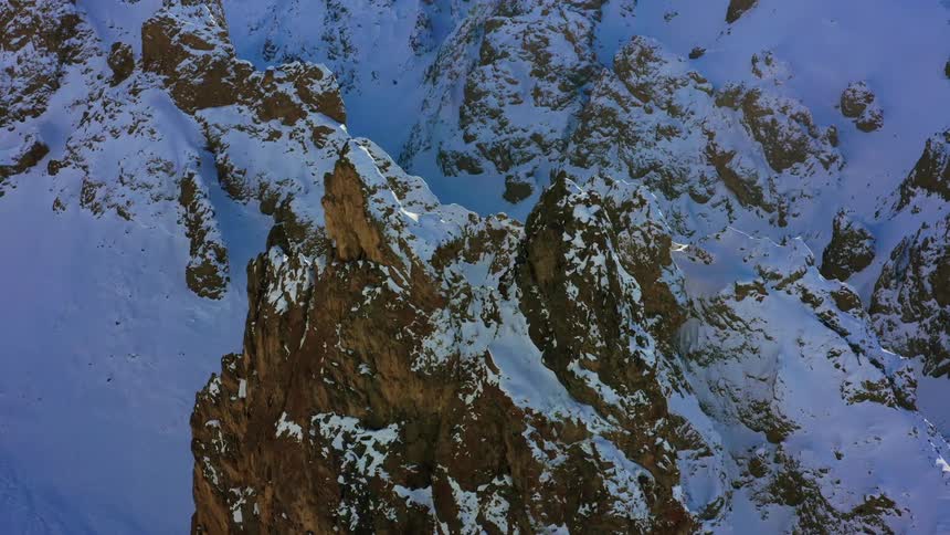 An aerial view of a snow covered mountain is displayed
