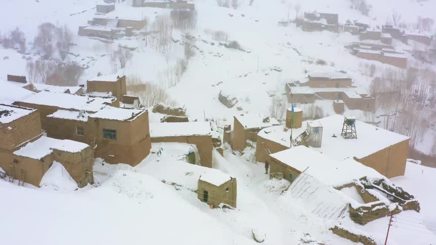 Snow covered buildings on a hillside in snow storm during the day